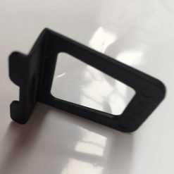 A black, rectangular Finger Tab is positioned upright on a reflective white surface, casting a slight shadow. The tab has a small extension on one end.