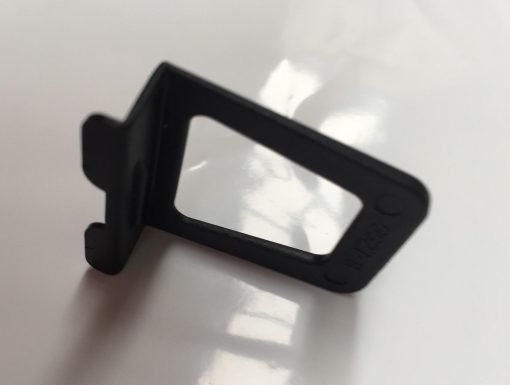 A black, rectangular Finger Tab is positioned upright on a reflective white surface, casting a slight shadow. The tab has a small extension on one end.